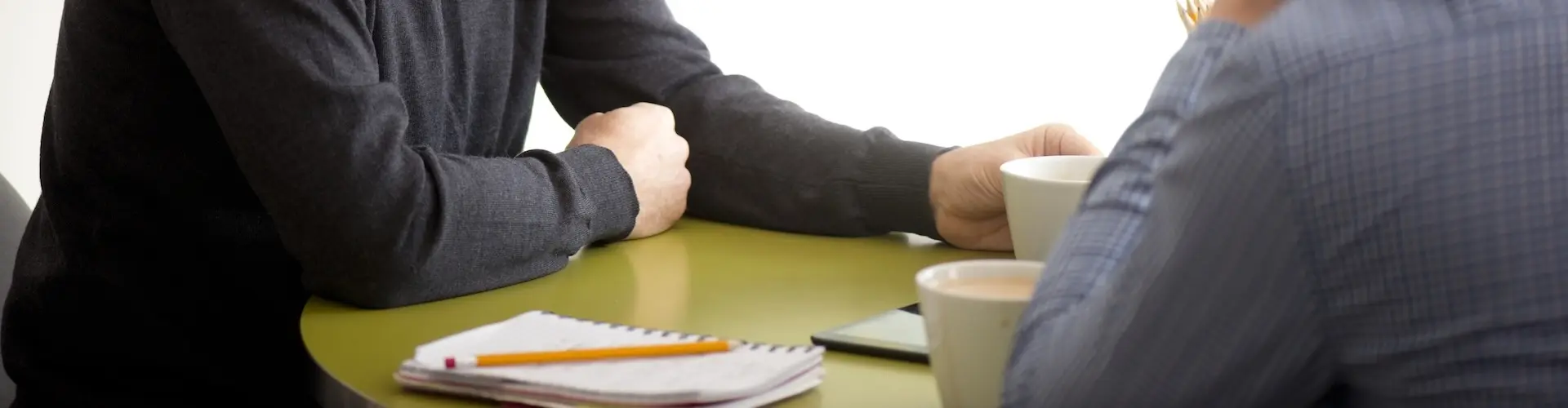 Cut off photograph of two men talking in an office environment