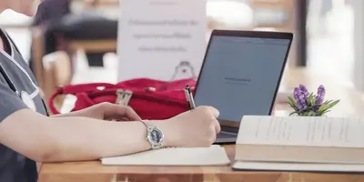 Medical student studying with laptop and textbook
