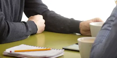Cut off photograph of two men talking in an office environment