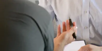 Cut off photograph of two men talking in an office environment